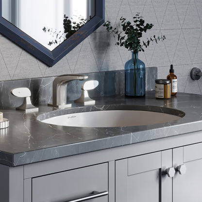 Oval under-mount bathroom sink in white, installed in gray stone countertop with modern faucet.