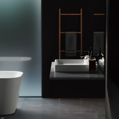 Large rectangular white vessel sink on black countertop with modern faucet and mirror reflection.