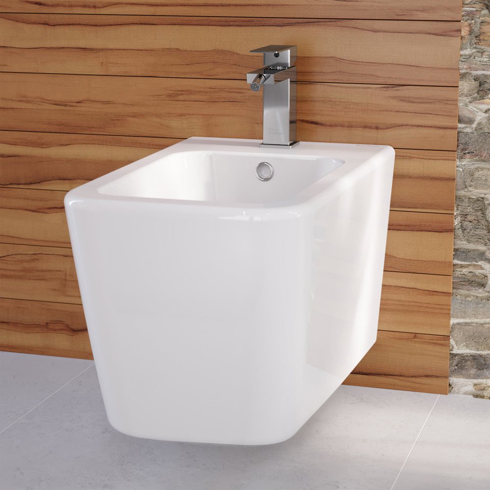 Wall-mounted white bidet with chrome single-handle Concorde faucet and wooden accent wall.