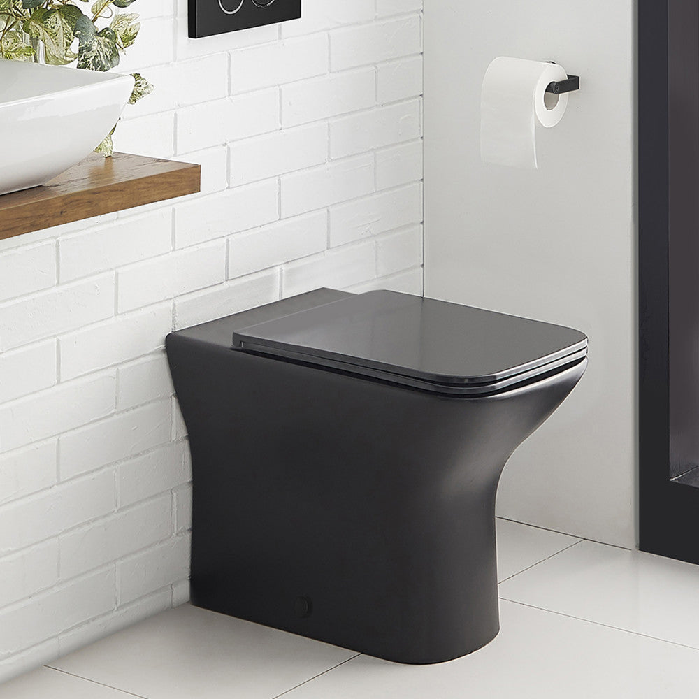 Elongated back-to-wall toilet in matte black with skirted trapway and soft-close seat.