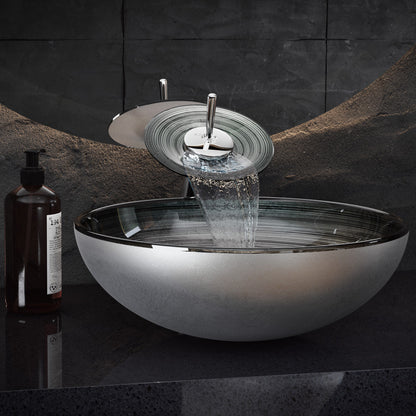 Smoky gray glass vessel sink with waterfall faucet, round bowl design, modern bathroom fixture.