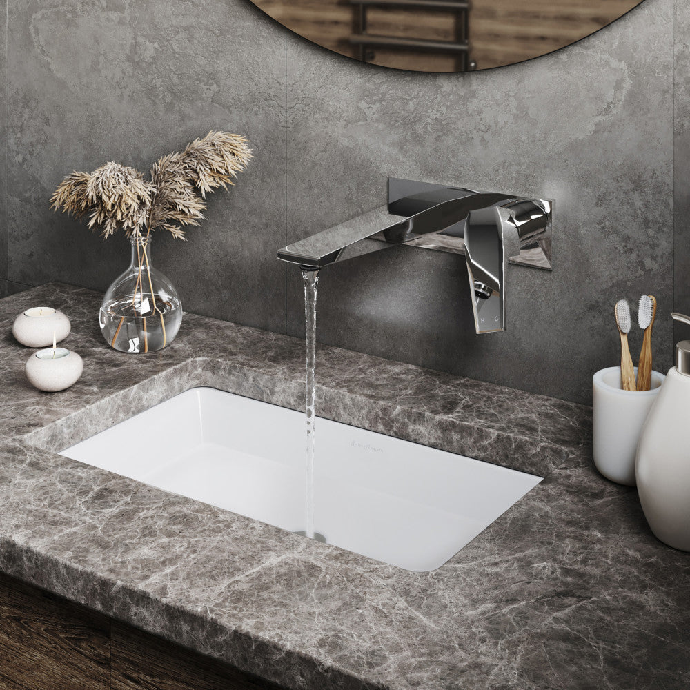 Wall-mount single-handle bathroom faucet in chrome with water flowing over rectangular white sink.