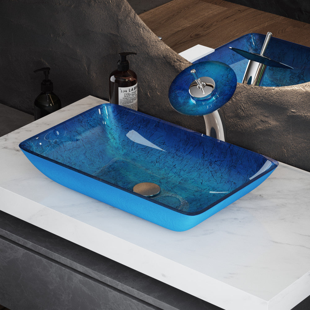 Rectangular ocean blue glass vessel sink with single-handle chrome faucet on marble countertop.