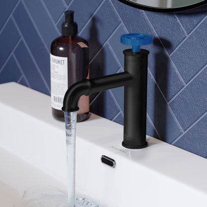 Single-handle bathroom faucet in matte black with distinctive blue wheel handle, mounted on white sink with running water.