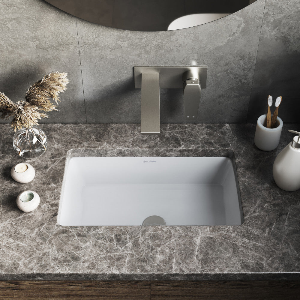 Rectangular white under-mount bathroom sink installed in gray marble countertop with modern wall-mounted faucet.