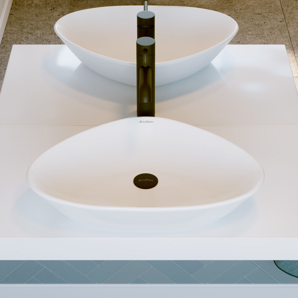 White oval ceramic vessel sink with black single-handle faucet on white countertop.