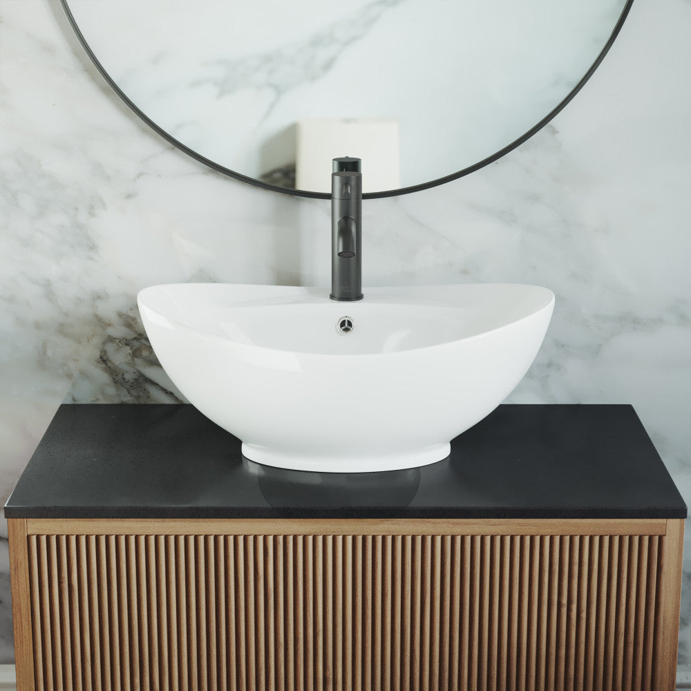 Oval white ceramic vessel sink with smooth curved edges on wooden vanity with black countertop.
