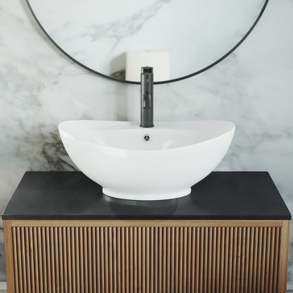 Oval white ceramic vessel sink with smooth curved edges on wooden vanity with black countertop.