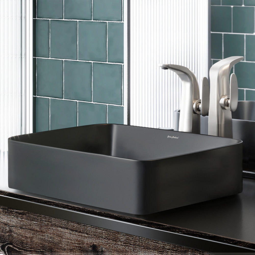 Matte black rectangular ceramic vessel sink on dark wood countertop with silver faucet.