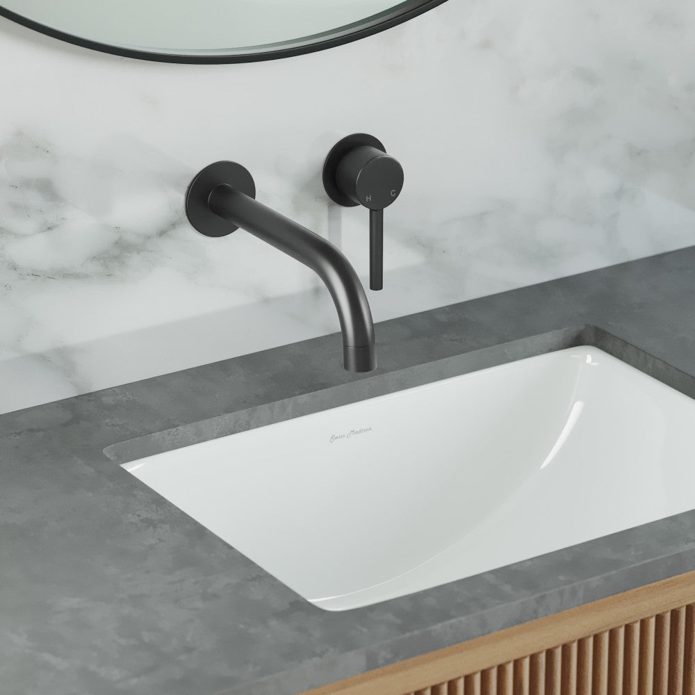 Wall-mount bathroom faucet in matte black, single handle, curved spout over rectangular undermount sink.