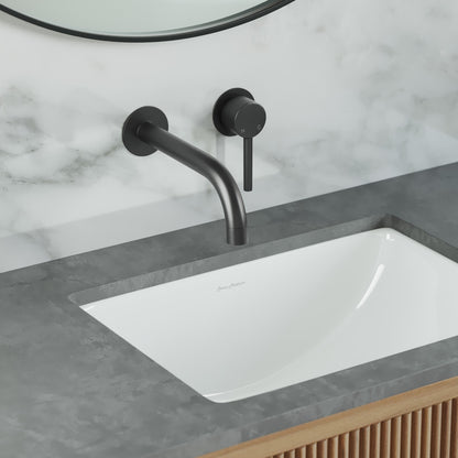 Wall-mount bathroom faucet in matte black, single handle, curved spout over rectangular undermount sink.