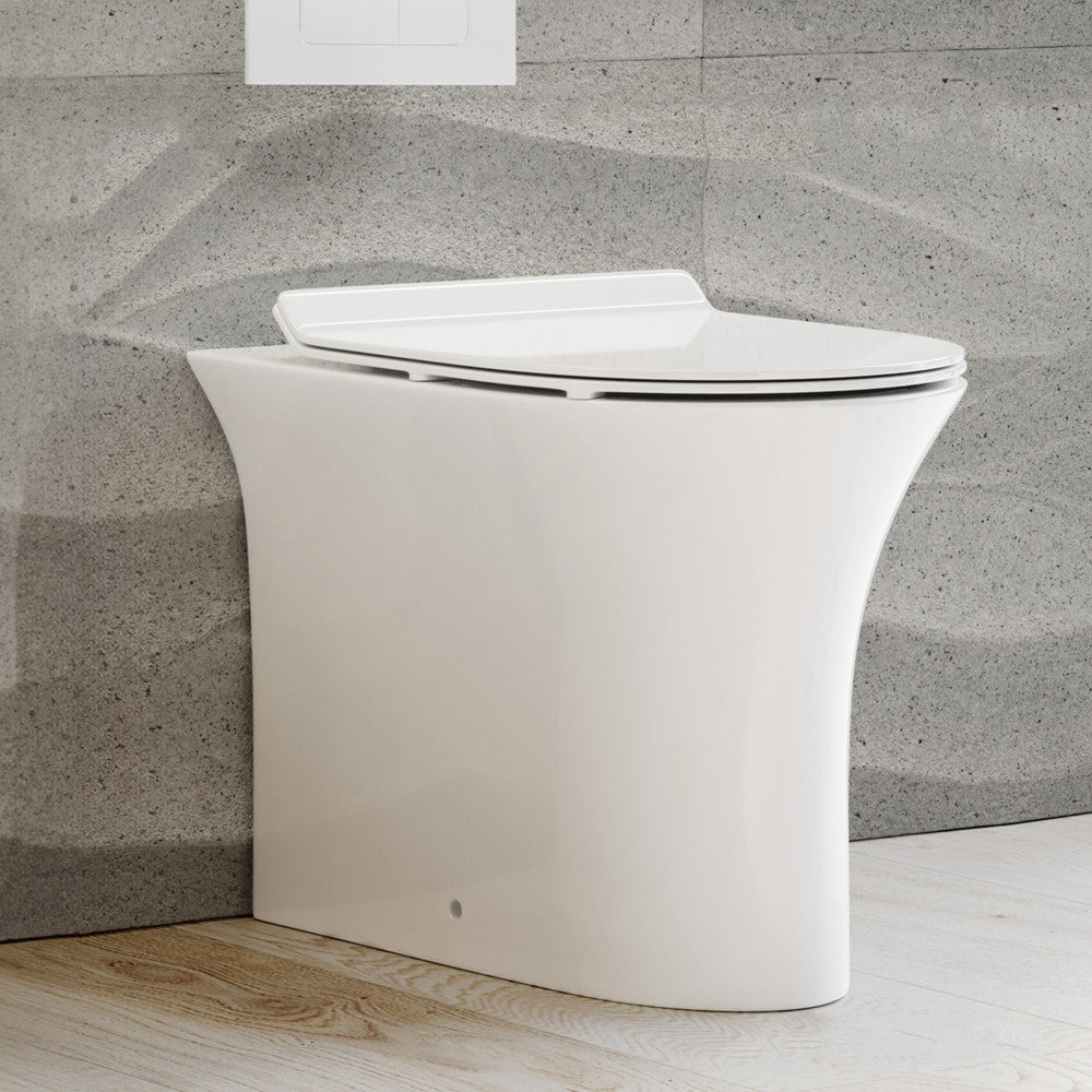 Elongated back-to-wall toilet bowl with smooth skirted trapway and soft-close seat in white ceramic.
