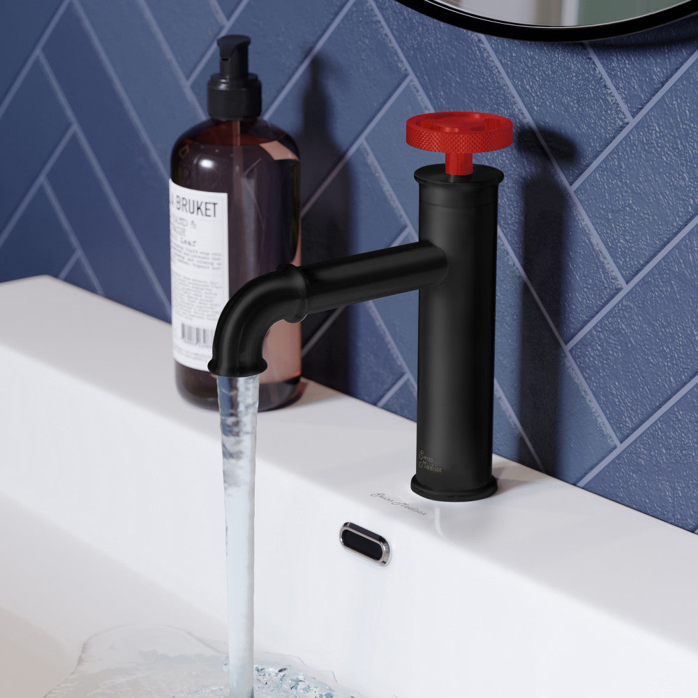 Single-handle bathroom faucet in matte black with distinctive red handle, running water from spout.