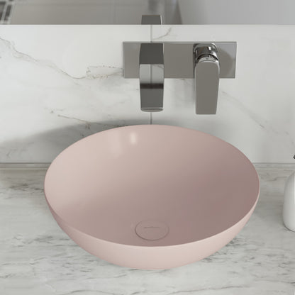 Matte pink ceramic vessel sink with round shape and smooth matte finish on marble countertop.